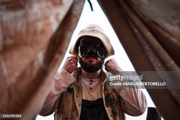 Performer puts on his mask of Harlequin prior to stage a show from the Commedia Dell'Arte during the carnival in Venice on February 4, 2023.