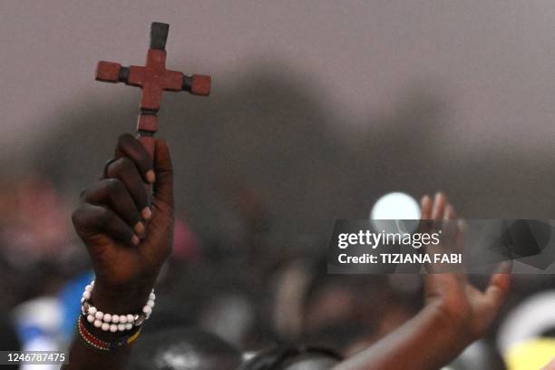 An attendee holds a cross during the Ecumenical prayer at the John Garang Mausoleum in Juba, South Sudan, on February 4, 2023. - Pope Francis is...