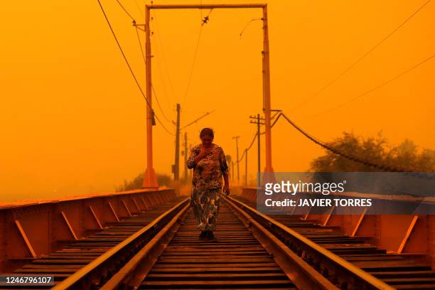 Woman walks on a bridge during the fires in Renaico, Araucania region, Chile on February 4, 2023. At least 23 people have died in hundreds of forest...
