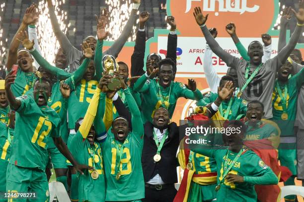 Senegal's players celebrate with the trophy on the podium after winning the 2022 African Nations Championship final football match between Algeria...