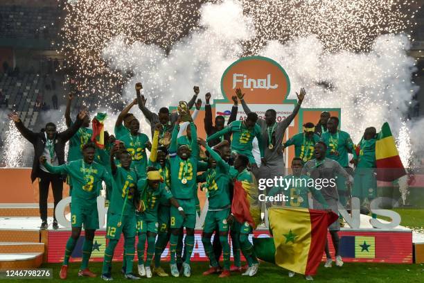 Senegal's players celebrate with the trophy on the podium after winning the 2022 African Nations Championship final football match between Algeria...