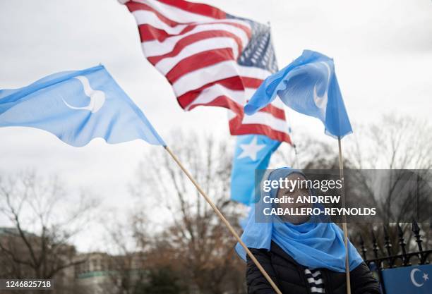 People hold up flags and signs during a protest in Washington, DC on February 5 marking the 26th anniversary of the 1997 Ghulja massacre in Ghulja...