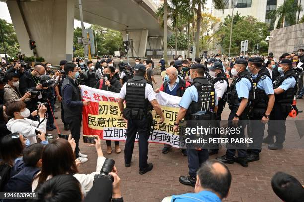 Members of the League of Social Democrats are stopped by police as they carry a banner outside a court in Hong Kong on February 6, 2023 as the trial...