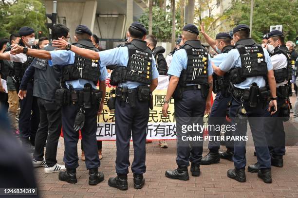 Members of the League of Social Democrats are surrounded by police as they carry a banner outside a court in Hong Kong on February 6, 2023 as the...