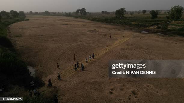 This aerial view shows refugee women crossing the dry beds of the White Volta river to their farms in Burkina Faso from Issakateng-Bausi, in Bawku,...