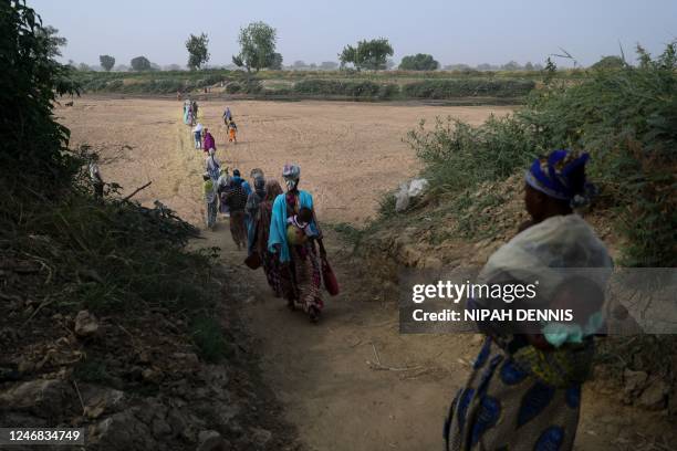 Women cross the dry bed of the White Volta river to their farms in Burkina Faso from Issakateng-Bausi, in Bawku, northern Ghana, on December 7, 2022....