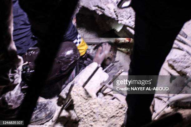 Rescuers try to free a young boy from the rubble of a collapsed building follwoing an earthquake, in the Syrian border town of Azaz in the rebel-held...