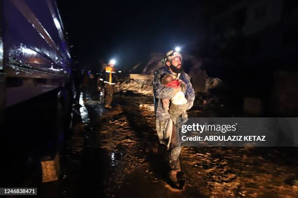 Member of the Syrian civil defence, known as the White Helmets, carries a child rescued from the rubble following an earthquake in the town of...