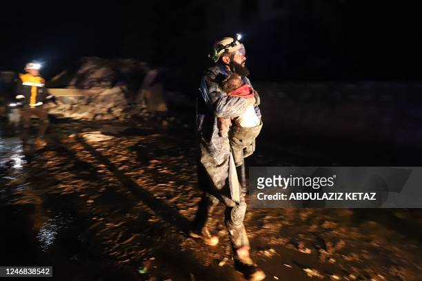 Member of the Syrian civil defence, known as the White Helmets, carries a child rescued from the rubble following an earthquake in the town of...