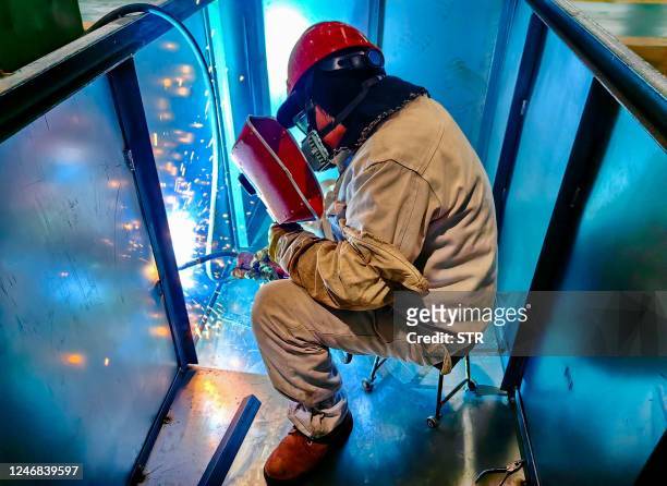 Worker welds a waste-to-energy incinerator at a factory in Nantong, in China's eastern Jiangsu province on February 6, 2023. - China OUT / China OUT