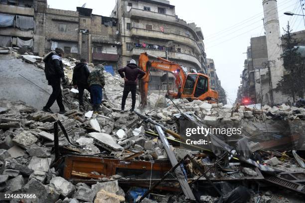 Onlookers watch as rescue teams look for survivors under the rubble of a collapsed building after an earthquake in the regime-controlled northern...