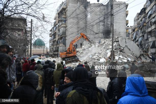 Onlookers watch as rescue teams look for survivors under the rubble of a collapsed building after an earthquake in the regime-controlled northern...