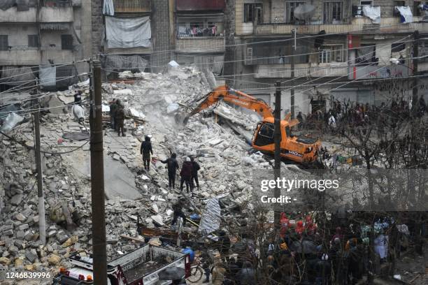 People watch as rescue teams look for survivors under the rubble of a collapsed building after an earthquake in the regime-controlled northern Syrian...