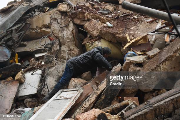 Man looks for survivors under the rubble of a collapsed building after an earthquake in the regime-controlled northern Syrian city of Aleppo on...