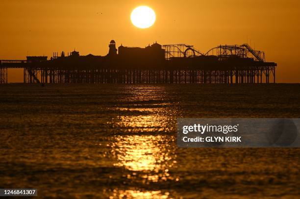 The sun rises above the Palace Pier in Brighton, southern England, on February 6, 2023.