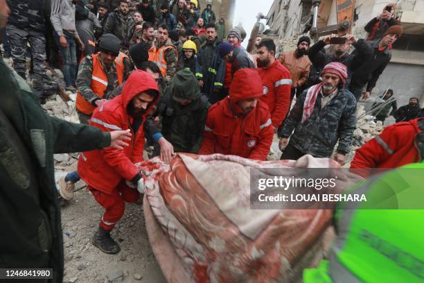 Syrian rescue teams carry a casualty picked up from the rubble after an earthquake in the government-controlled central Syrian city of Hama on...