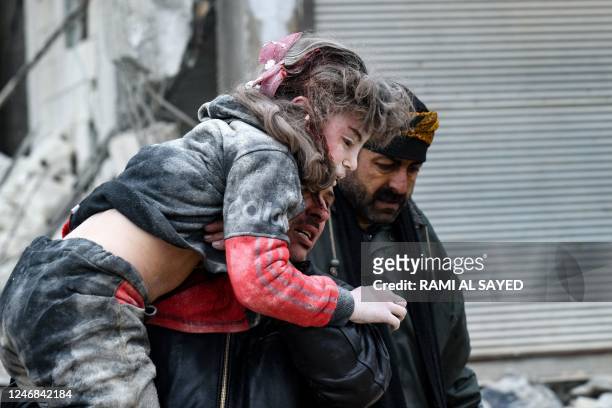 Graphic content / TOPSHOT - Residents carry an injured child from the rubble of a collapsed building following an earthquake in the town of...