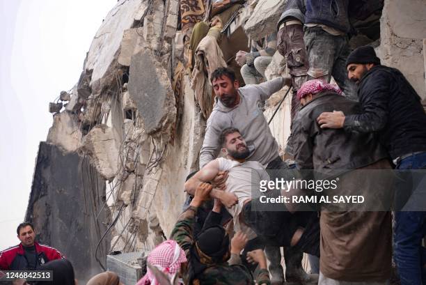Residents retrieve an injured man from the rubble of a collapsed building following an earthquake in the town of Jindayris, in the countryside of...
