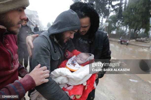 Graphic content / TOPSHOT - A Syrian man weeps as he carries his son who was killed in an earthquake in the town of Jindayris, in the countryside of...