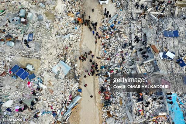 This aerial view shows residents searching for victims and survivors amidst the rubble of collapsed buildings following an earthquake in the village...