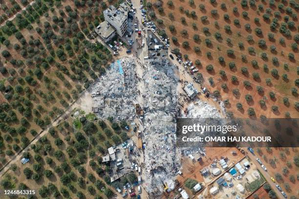 This aerial view shows residents searching for victims and survivors amidst the rubble of collapsed buildings following an earthquake in the village...