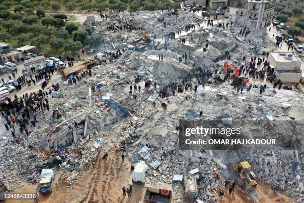 This aerial view shows residents searching for victims and survivors amidst the rubble of collapsed buildings following an earthquake in the village...