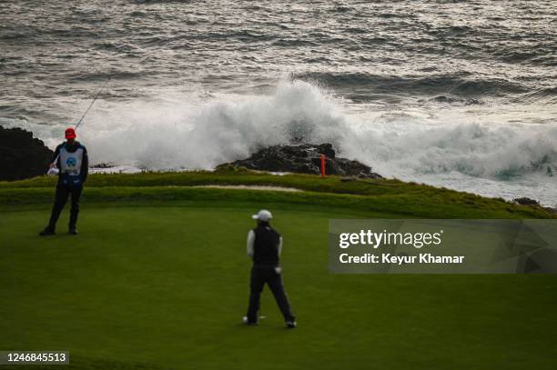 Kurt Kitayama putts on the seventh hole green as waves crash behind him during the final round of the AT&T Pebble Beach Pro-Am at Pebble Beach Golf...