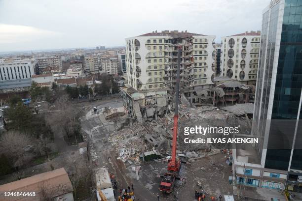 Rescue workers and volunteers use a crane as they conduct search and rescue operations in the rubble of a collasped building, in Diyarbakir on...