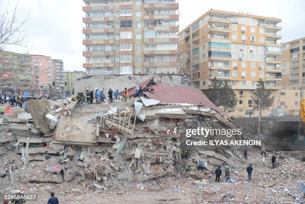 Rescue workers and volunteers conduct search and rescue operations in the rubble of a collasped building, in Diyarbakir on February 6 after a...