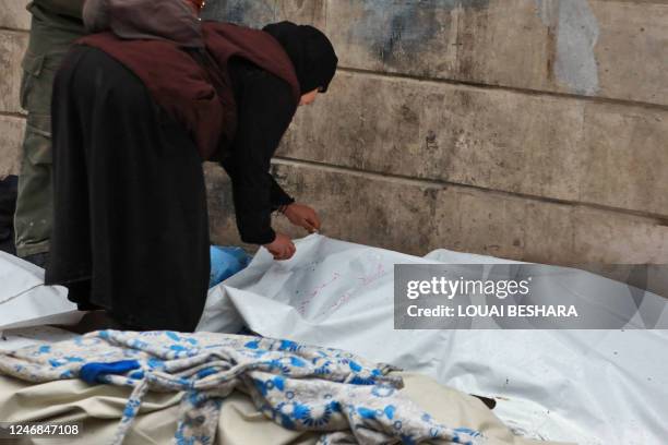 Graphic content / A Syrian woman checks a body lying on the street outside a morgue in the city of Aleppo following a deadly earthquake on February...