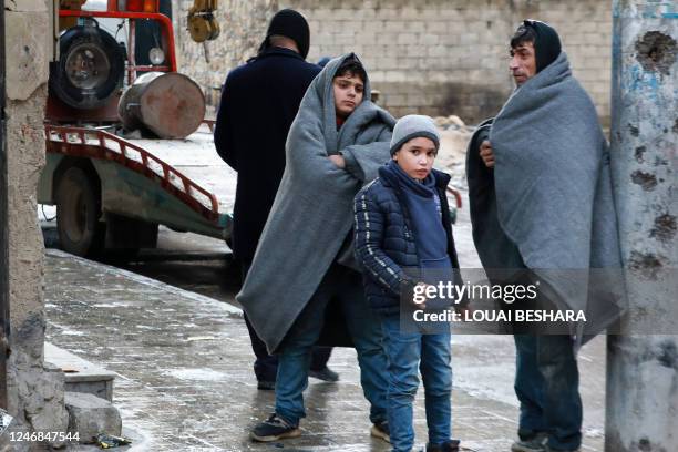 Graphic content / A Syrian man and children gather outside on a street following a deadly earthquake on February 6, 2023 in Aleppo. - The Syrian...