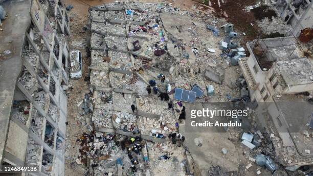 An aerial view of a collapsed buildings as personnel and civilians conduct search and rescue operations in Cenderes district of Aleppo, Syria after...