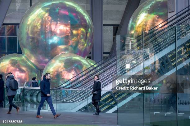City office workers ride escalators alongside an artwork entitled 'Evanescent' is being displayed in January and February beneath at the Leadenhall...