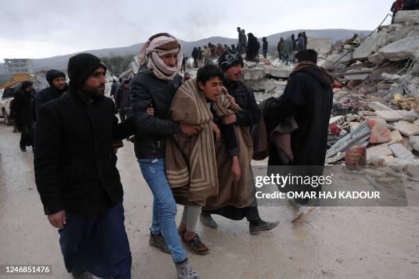 Youth is comforted as residents and rescuers search for victims and survivors following an earthquake in the village of Besnaya in Syria's rebel-held...
