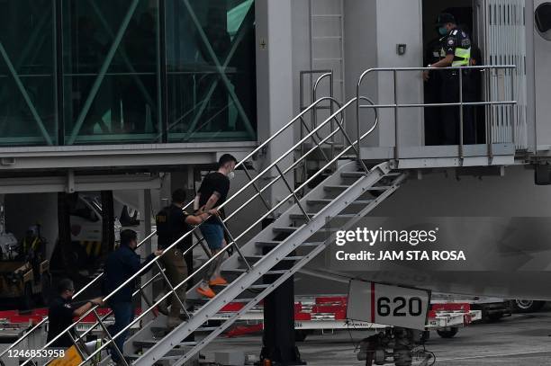 Security personnel escort one of the two Japanese fugitives as they board a plane at the airport in Metro Manila on February 7, 2023.