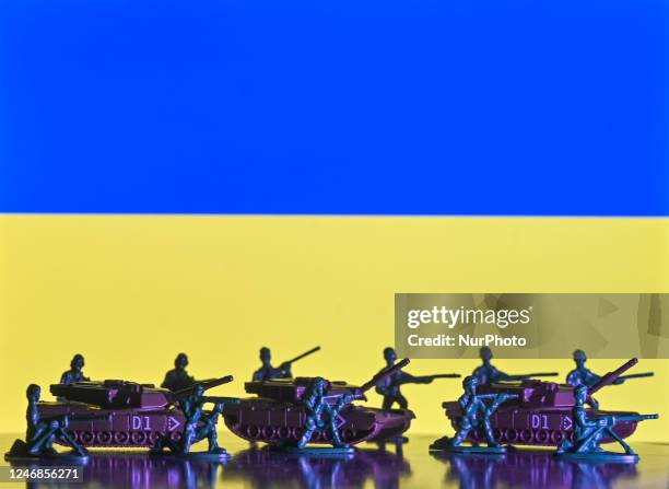 Illustration of a mini replica representing tanks and figures of soldiers, seen in front of the Ukrainian flag, displayed on a computer screen. On...