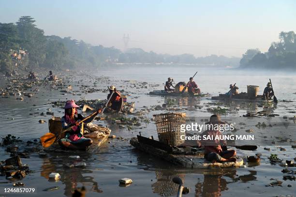 This photo taken on January 14, 2023 shows waste collectors paddling polystyrene boats as they look for plastic and glass to recycle in Pazundaung...