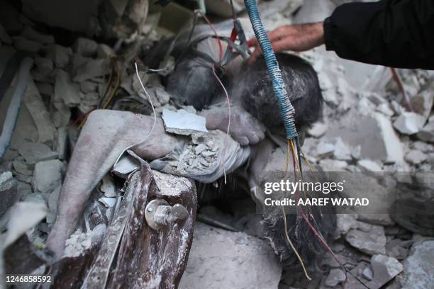 Graphic content / TOPSHOT - The bodies of two victims are trapped amidst the rubble of a collapsed building late on February 6, 2023 in the town of...