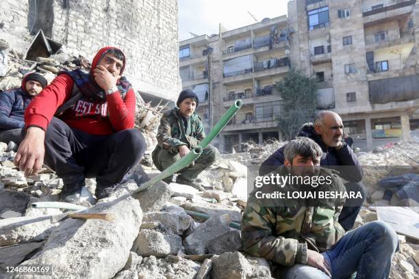 Graphic content / People watch as rescue teams search for victims and survivors stuck under the rubble of collaped buildings in the government-held...