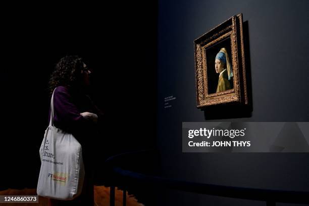 Women looks a painting by the Dutch master Johannes Vermeer titled, 'Girl with a pearl earing' at the Rijksmuseum in Amsterdam on February 6, 2023. -...
