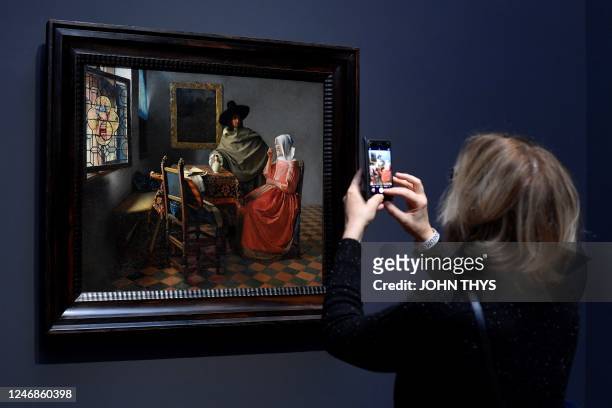 Women takes a picture of a painting by the Dutch master Johannes Vermeer titled, 'A glass of wine' at the Rijksmuseum in Amsterdam on February 6,...
