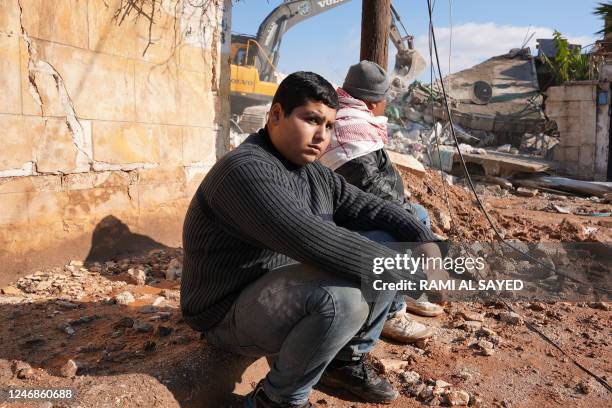 Syrians sit next to the rubble of a house in which one entire family except a newborn baby was killed, on February 7 in the town of Jindayris, in the...