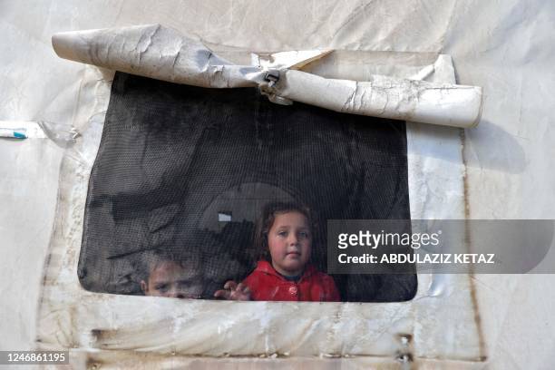 Syrian children look out of the window of a tent window at an emergency shelter in the center of the city of Maarat Misrin, in the rebel-held...