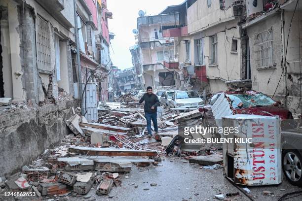 Man runs along a street strewn with debris, in Hatay, the day after a 7.8-magnitude earthquake struck the country's southeast on February 7, 2023. -...