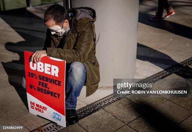 Driver working for Uber holds a placard during a protest against what they consider to be unfair treatment by the taxi company in front of Uber's...