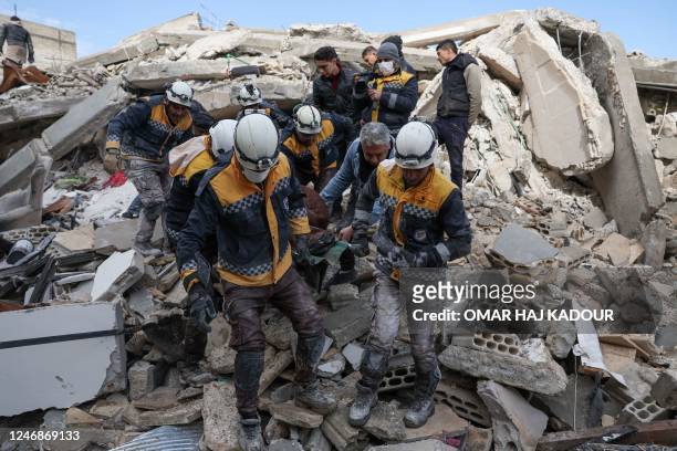 Members of the Syrian civil defence, known as the White Helmets, transport a casualty from the rubble of buildings in the village of Azmarin in...