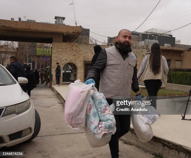 People carry packages to be sent to Turkiye as an aid campaign launches in Sulaymaniyah, Iraq following 7.7 and 7.6 magnitude earthquakes hit...