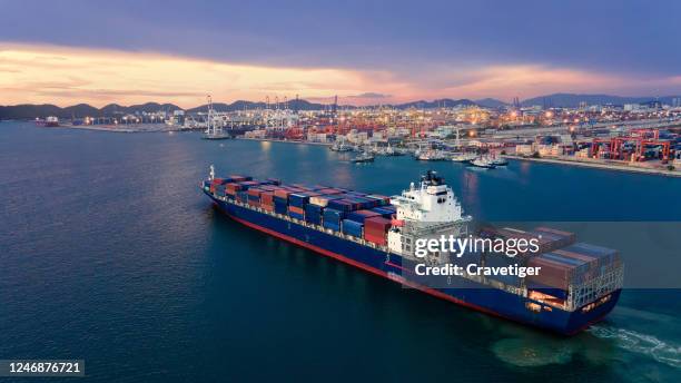 aerial view drone shot of a massive vessel in dock at the port of thailand, full of multicoloured shipping containers. boat 're going to push and pull ship with container to deep sea. - barge stock-fotos und bilder