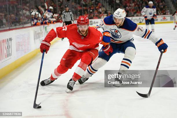 Michael Rasmussen of the Detroit Red Wings skates with the puck past Vincent Desharnais of the Edmonton Oilers during the third period of an NHL game...