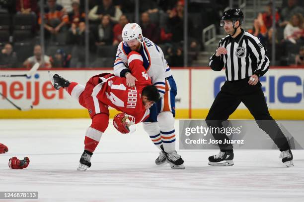 Robby Fabbri of the Detroit Red Wings fights with Brett Kulak of the Edmonton Oilers as linesmen Andrew Smith looks on during the third period of an...